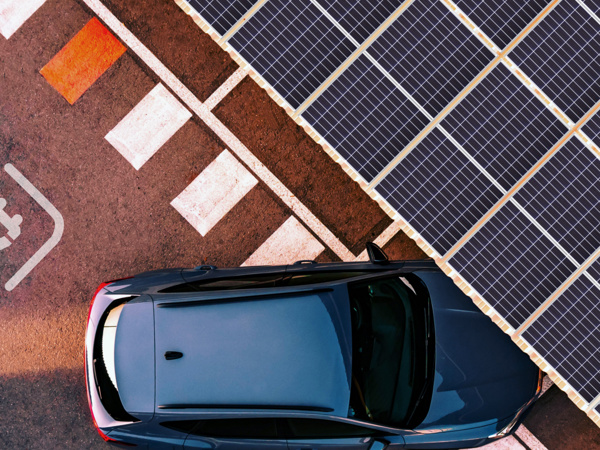 Fågelvy på en bil som kör in under ett tak av solpaneler