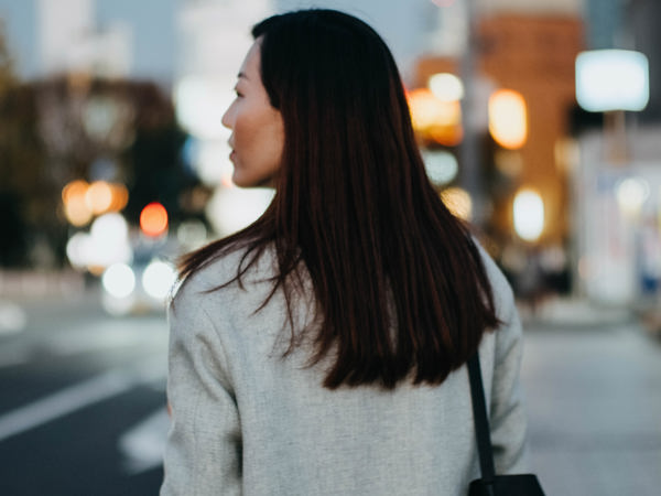Kvinna promenerar på trottoar