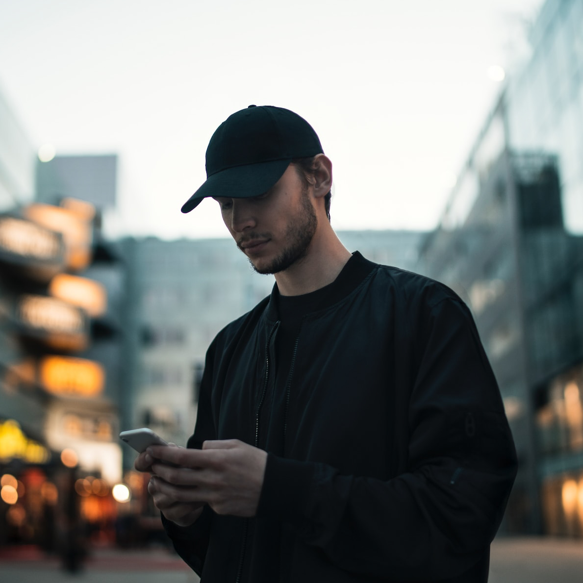 Ung man med keps tittar i mobilen