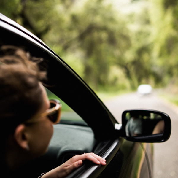 Kvinna med solglasögon i en bil i rörelse