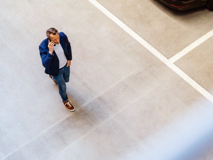 Ovanförperspektiv på en man som går och pratar i mobiltelefon i ett parkeringshus