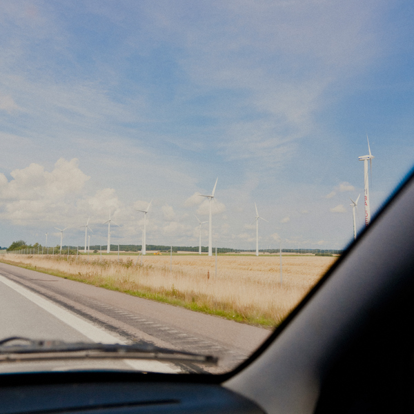 Vindkraftverk på en åker, sedda genom vindrutan på bil